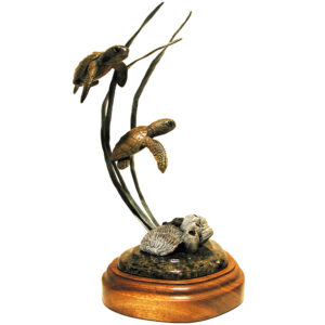 Bronze sculpture of two juvenile loggerhead sea turtles swimming upward among seagrass, on a round wood base