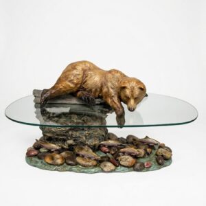 Bronze coffee table with a brown bear fishing in a stream beneath a glass top