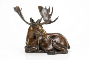 Moose Laying, an 8 inch bronze bull moose sculpture by Eric Thorsen, resting with legs folded beneath palmated antlers